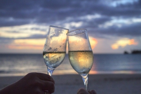 friends-toasting-with-champagne-flute-on-beach-at-sunset
